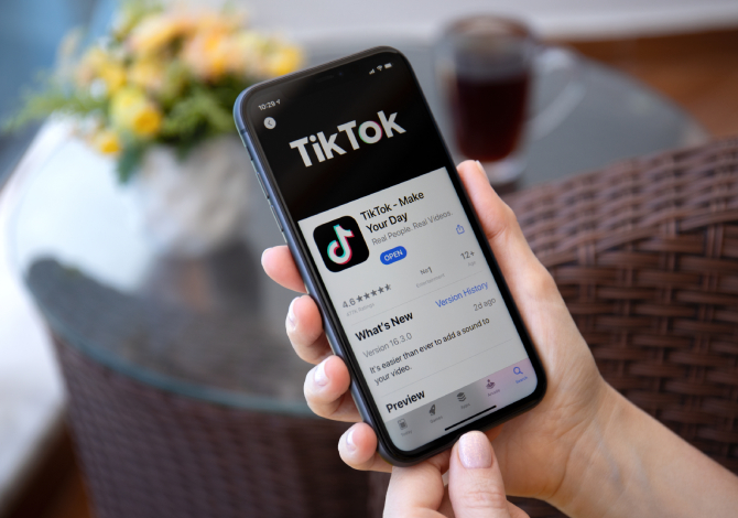 Hand holding phone displaying TikTok in the app store