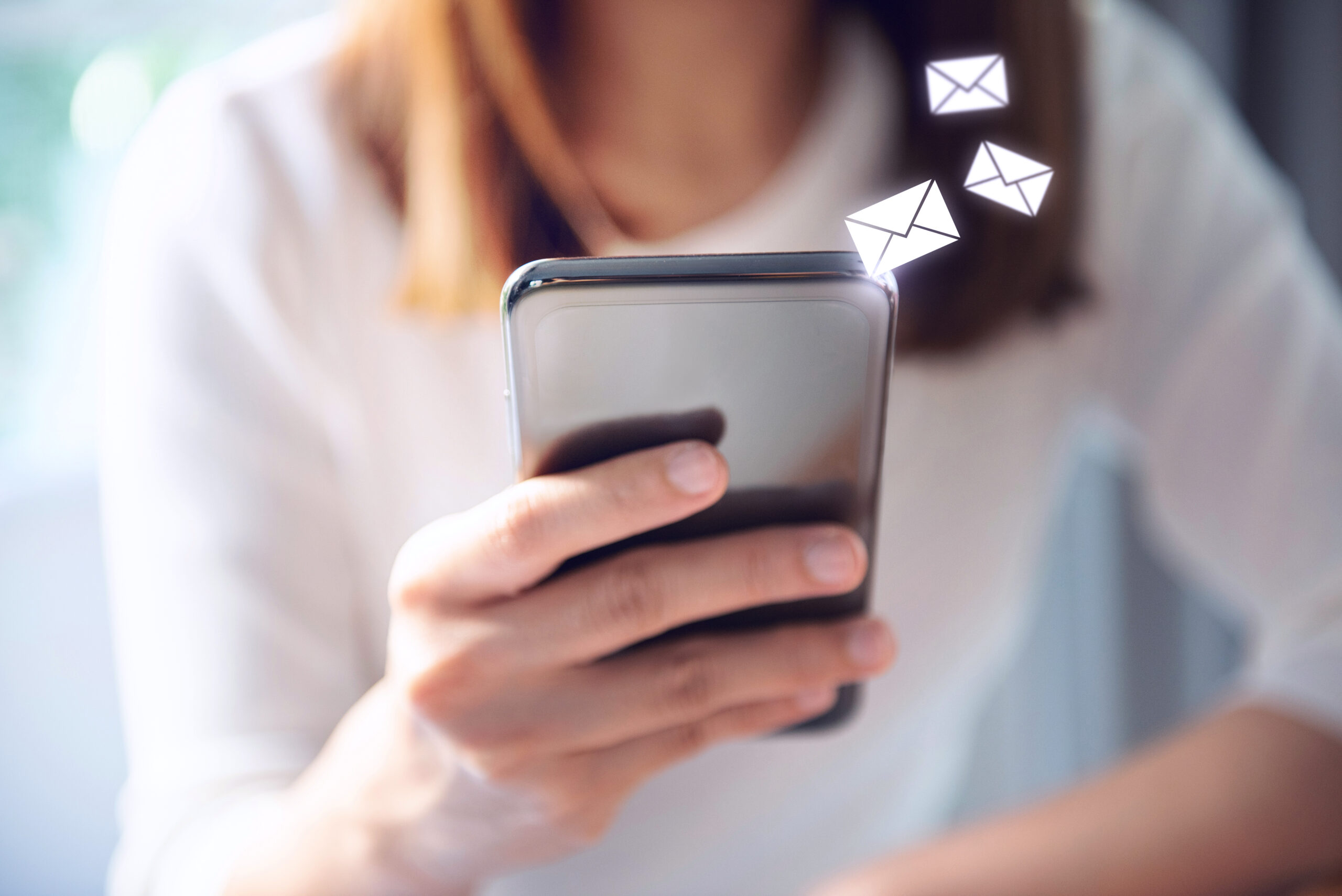 Close up of girl's hand holding smartphone with envelope message icons