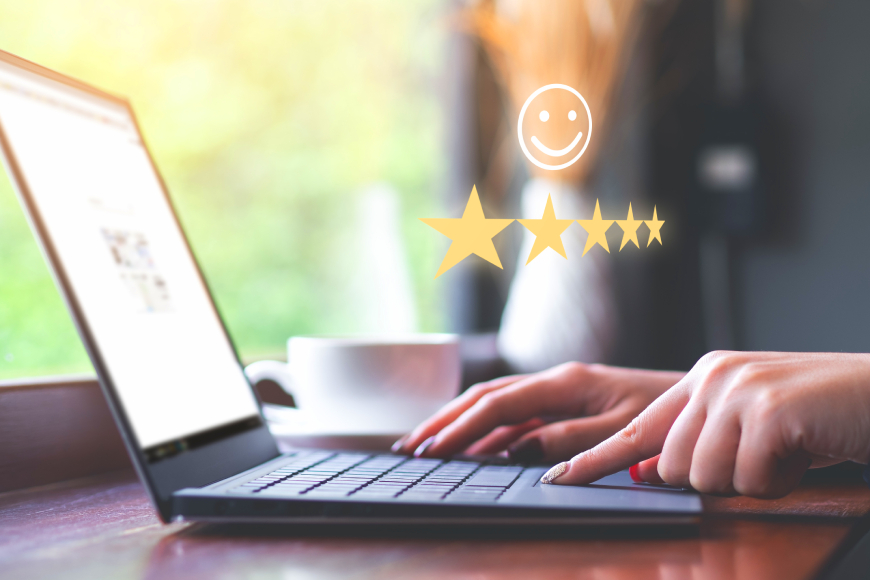 Close-up of female hands typing on a laptop with 5 gold stars and smiley face, satisfied customer