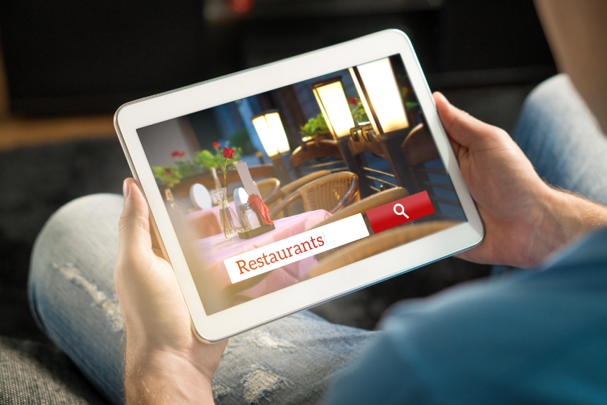 Close-up of male hands holding iPad tablet displaying restaurant search bar on screen