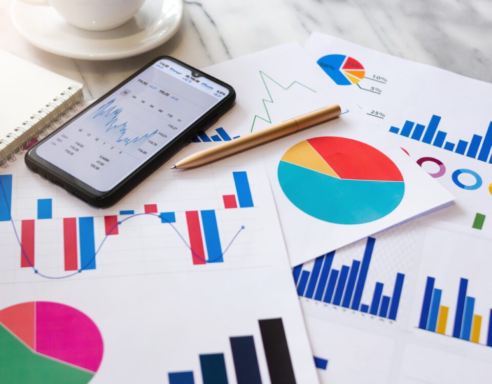 Graphs and charts on paper beside smartphone on desk