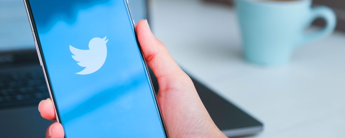 Hand holding smartphone with Twitter logo on screen