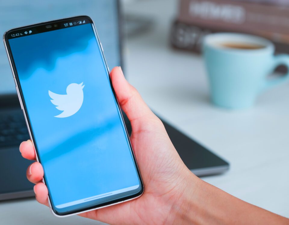 Hand holding smartphone with Twitter logo on screen