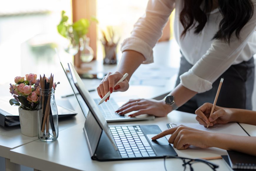 People pointing at iPad tablet on desk in office