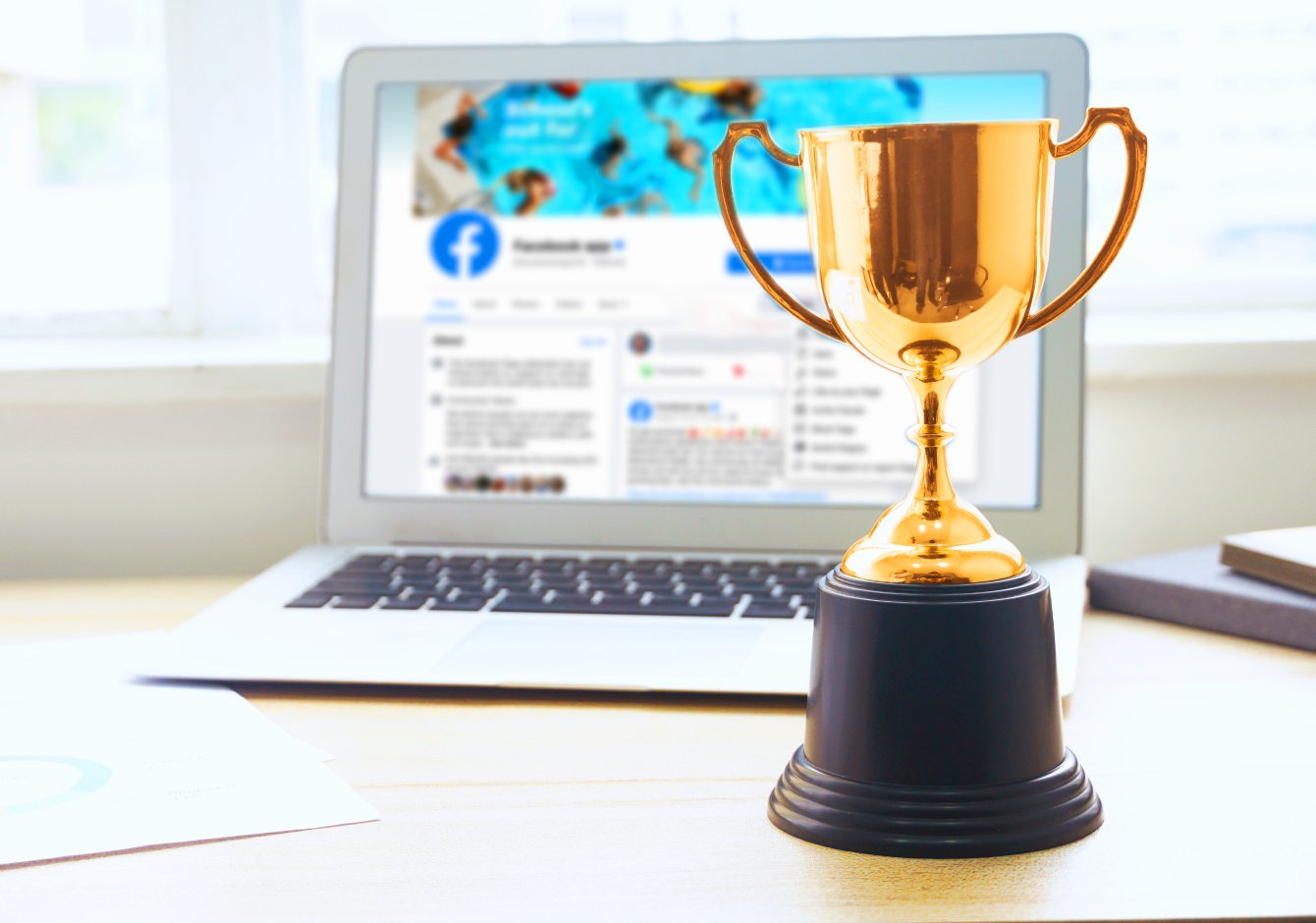 Gold trophy beside laptop with Facebook on screen