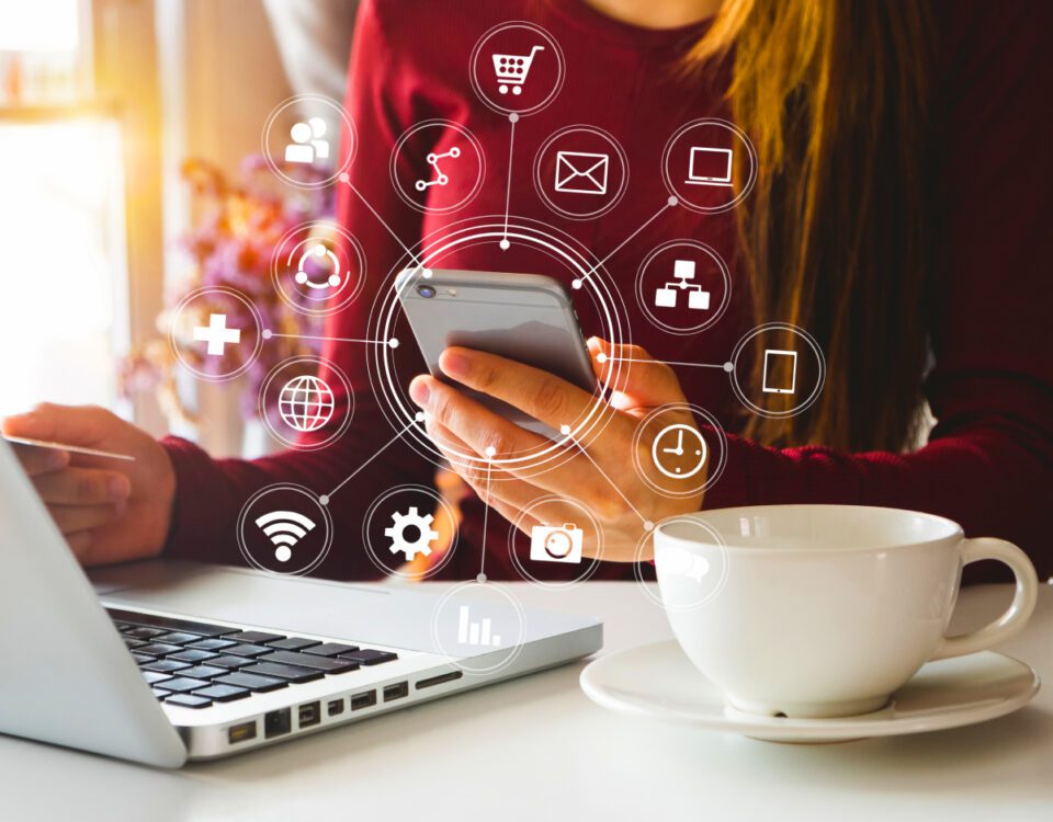 Girl's hand holding smartphone with laptop on desk