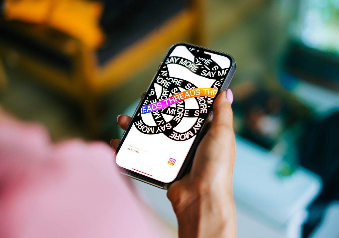 Hand holding smartphone with Threads app on screen