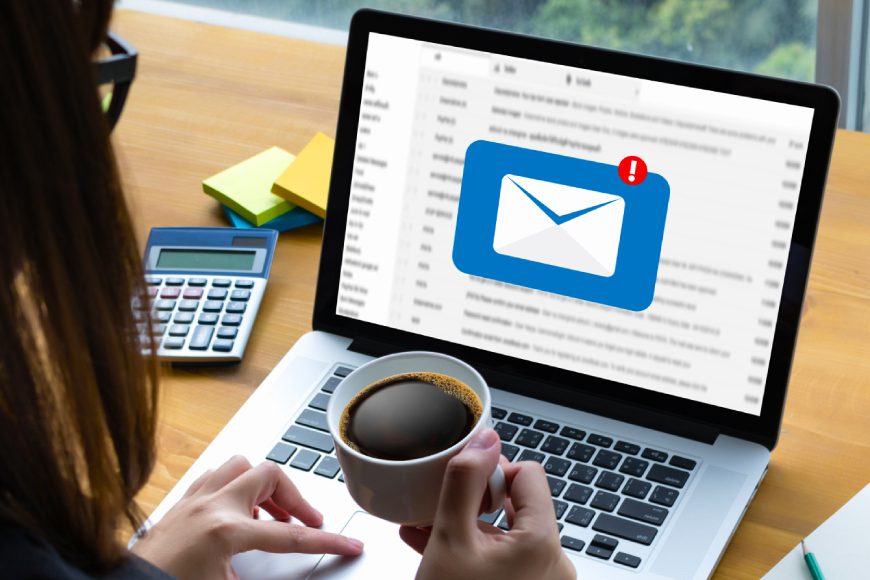 Woman sitting at desk looking at laptop with message inbox notification on screen