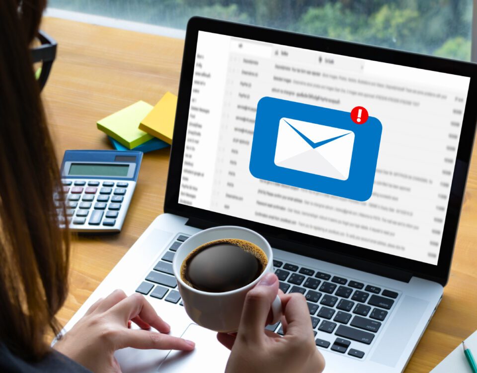 Woman sitting at desk looking at laptop with message inbox notification on screen