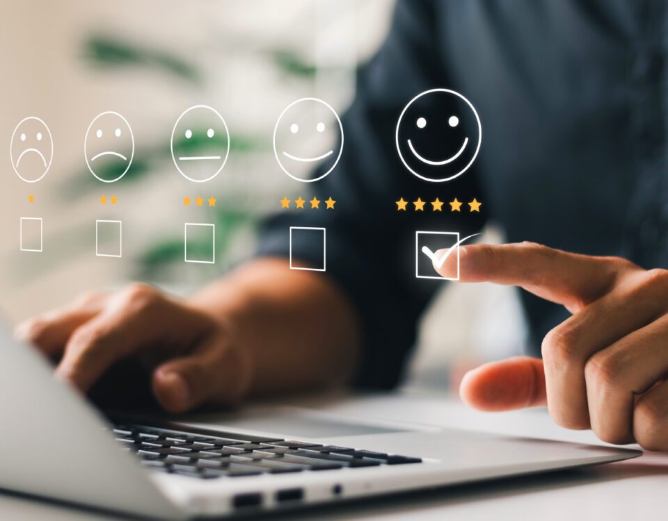 Person sitting at desk in front of laptop choosing 5 star smiley face rating