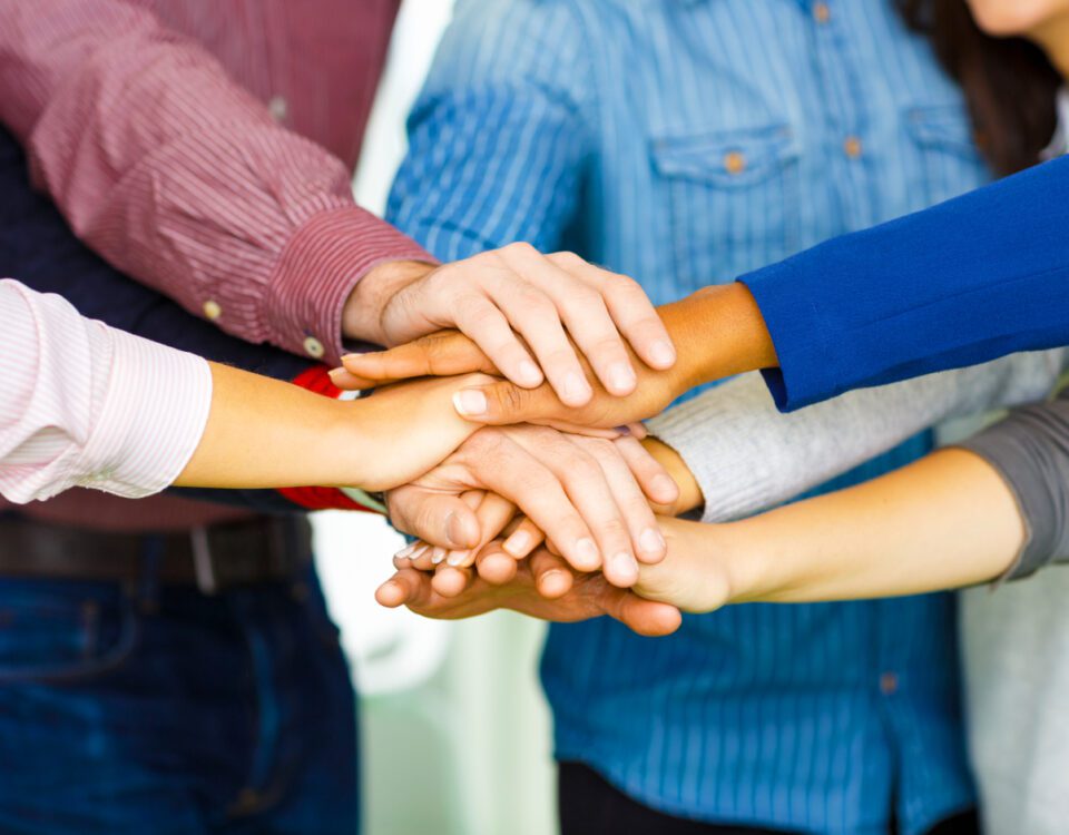 Team members putting their hands together in a circle to show support