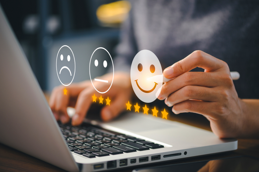 Person using laptop choosing smiley face icon from customer satisfaction survey rating options