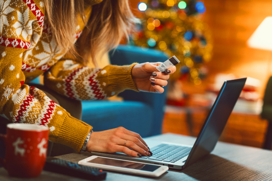 Woman holding credit card while using laptop to purchase Christmas gifts