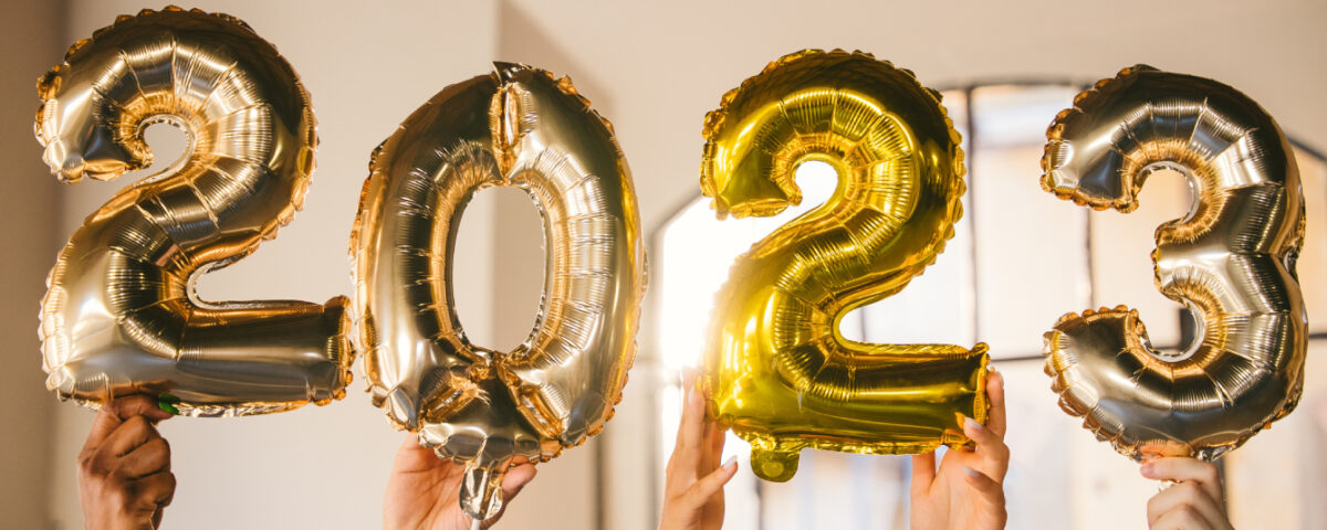 Hands holding gold number balloons that spell out 2023