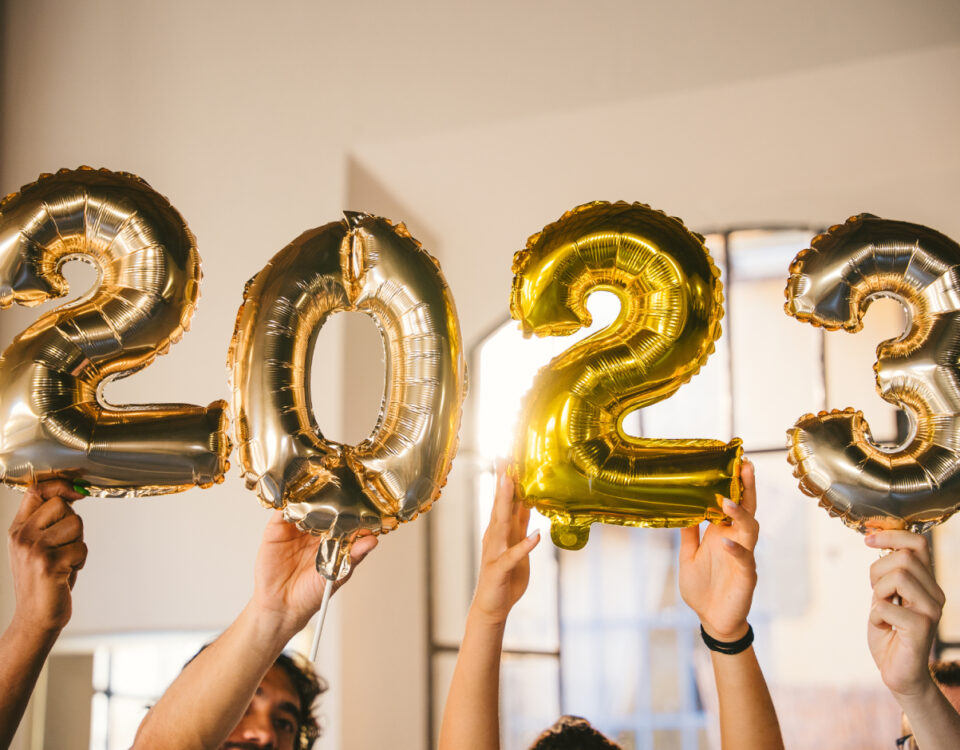 Hands holding gold number balloons that spell out 2023