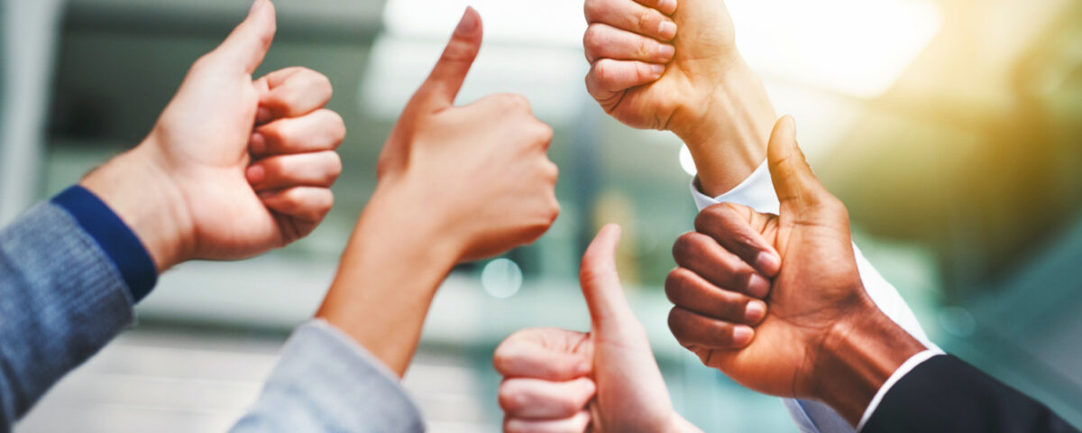 Employees in office putting their thumbs up
