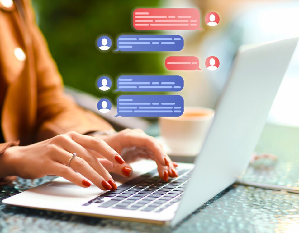Hands typing on laptop with live chat speech bubbles