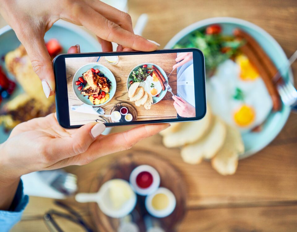 Hands holding smartphone taking photo of food in restaurant