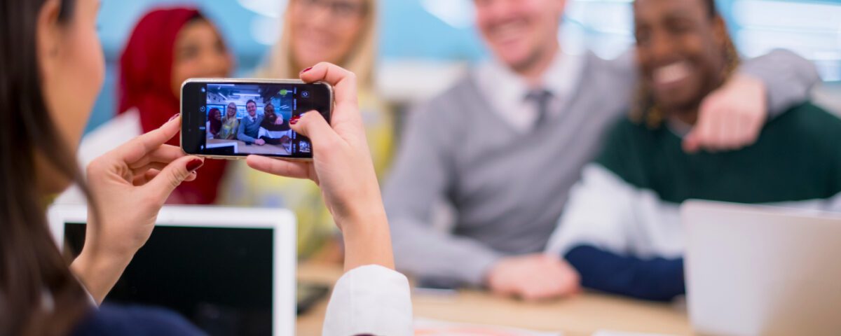 Woman using smartphone to take photo of team members in office