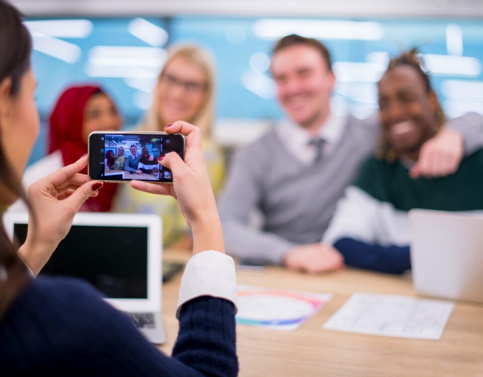 Woman using smartphone to take photo of team members in office