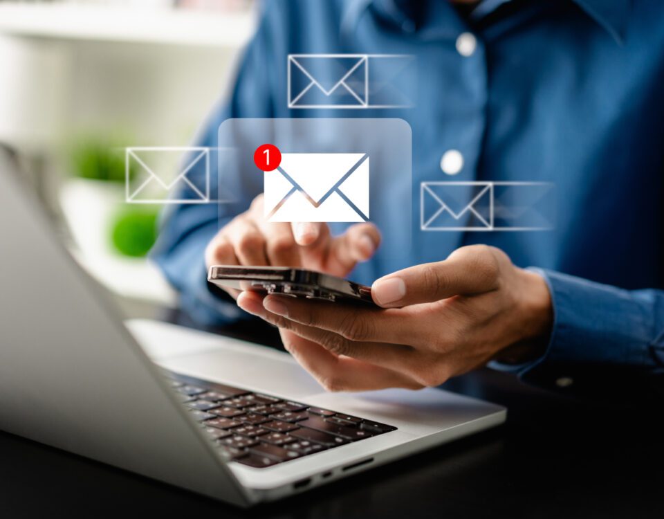 Hands holding smartphone in front of laptop with message notifications