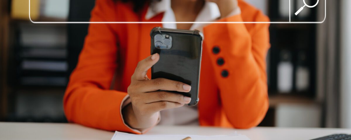 Woman sitting at desk using smartphone with search bar