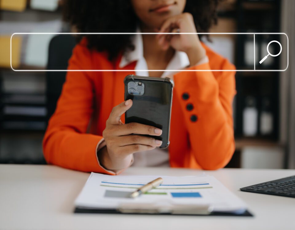 Woman sitting at desk using smartphone with search bar