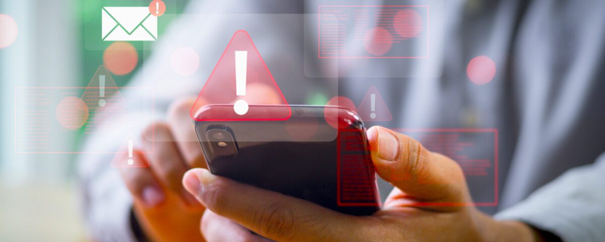 Hands holding smartphone with red exclamation mark alert symbol