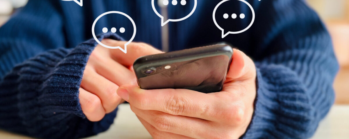 Hands holding smartphone with speech bubble message icons around it