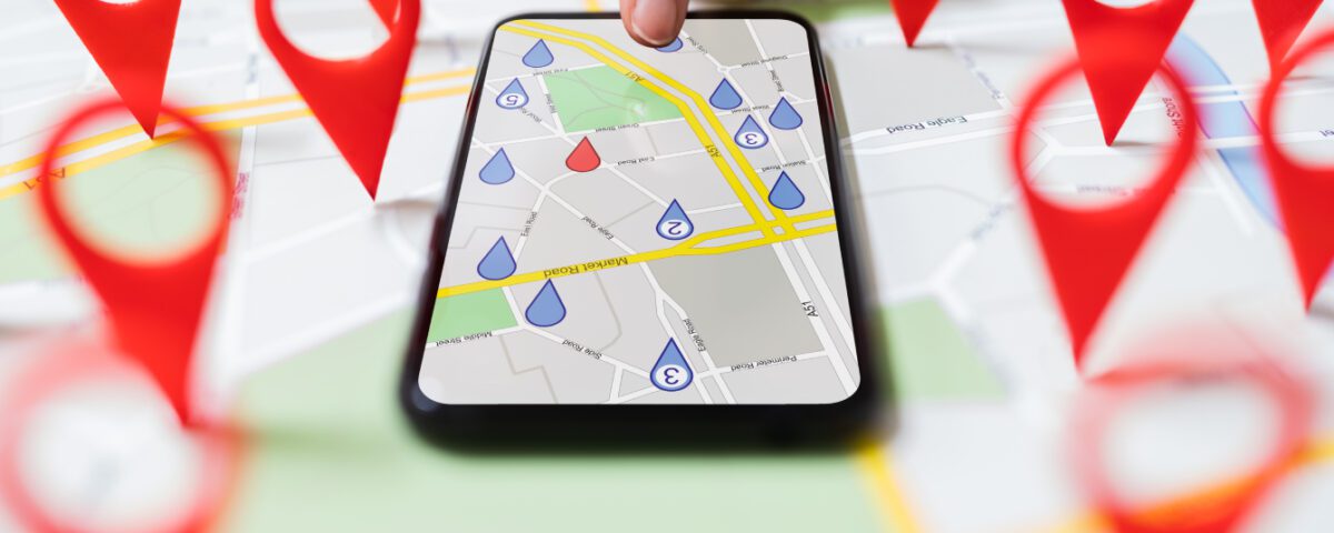 Finger tapping on smartphone screen showing a map with red location marker pins around it