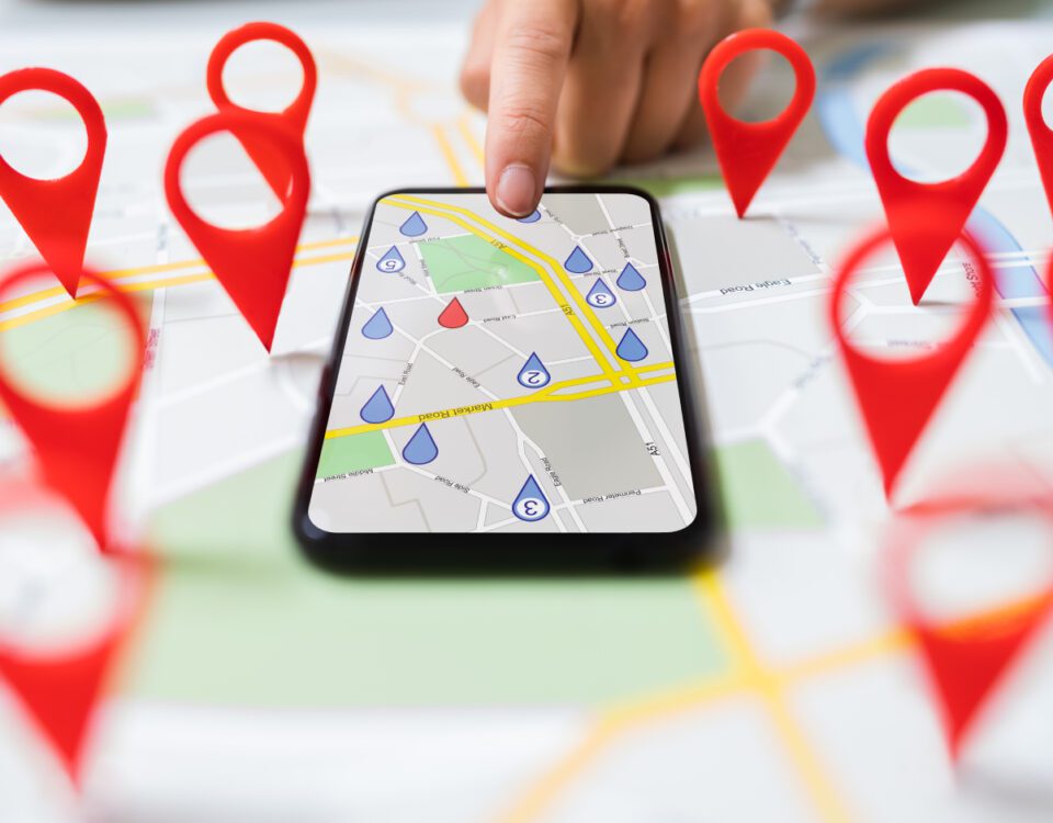 Finger tapping on smartphone screen showing a map with red location marker pins around it