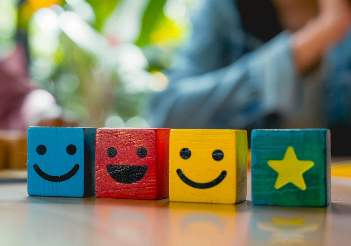 Coloured wooden blocks with happy faces on them on a desk