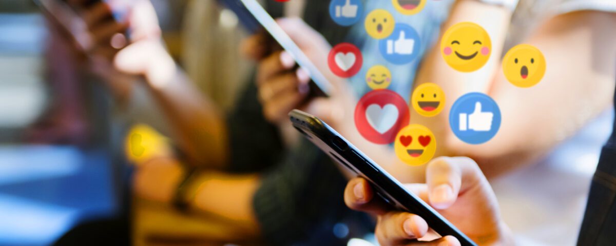 Row of people using smartphones with social media reaction emojis around