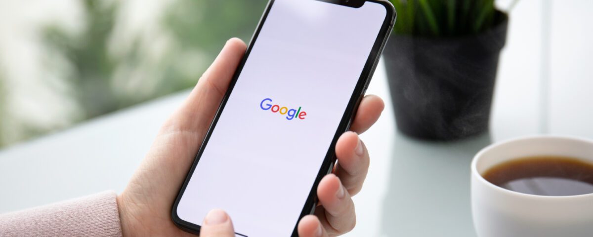 Hands holding smartphone with Google on screen