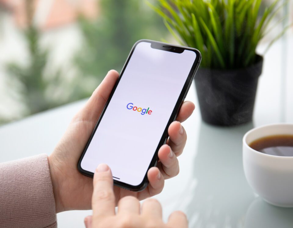 Hands holding smartphone with Google on screen