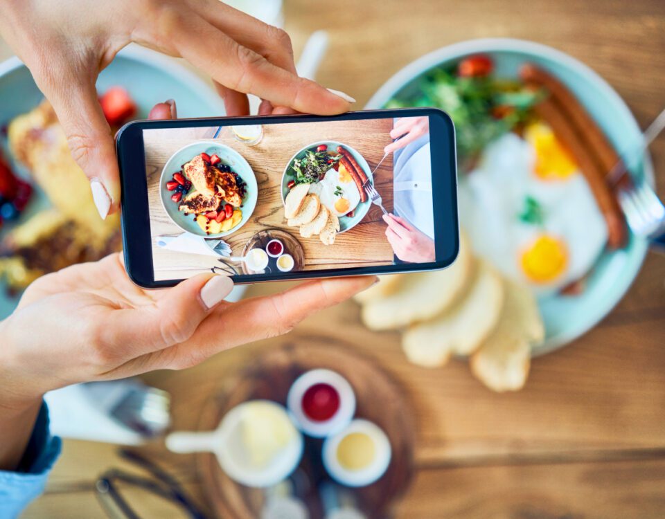 Hands holding smartphone taking photo of restaurant food
