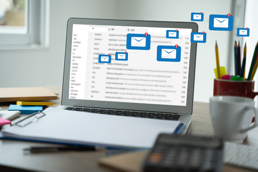 Laptop on desk with message envelope notification icons coming from screen