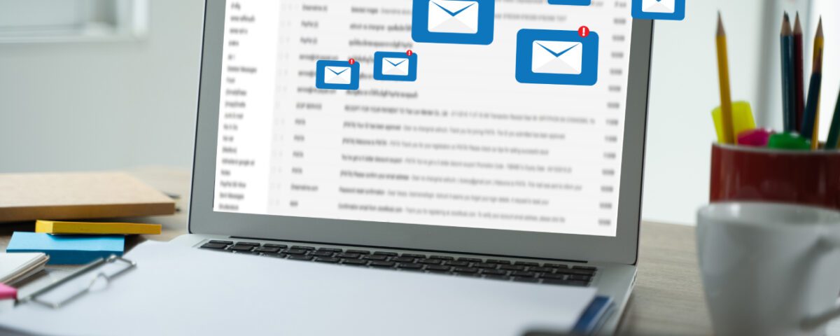 Laptop on desk with message envelope notification icons coming from screen