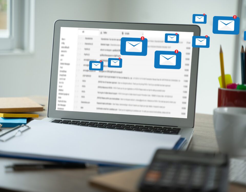 Laptop on desk with message envelope notification icons coming from screen