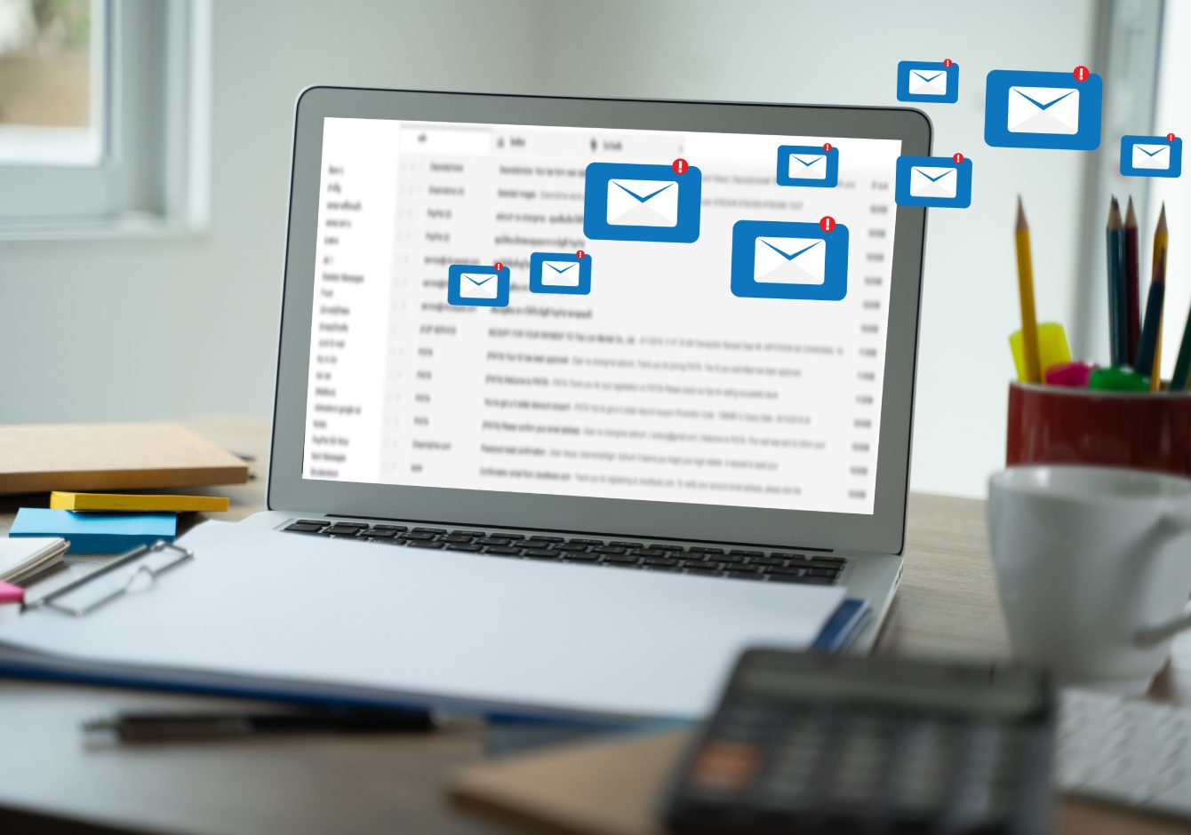 Laptop on desk with message envelope notification icons coming from screen