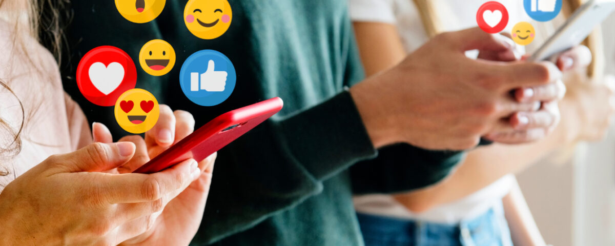 Row of people holding smartphones with social media reaction emojis around the screens