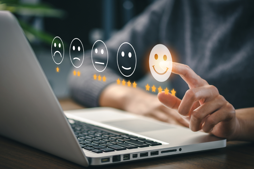Person sitting at desk using laptop and selecting five star satisfaction rating