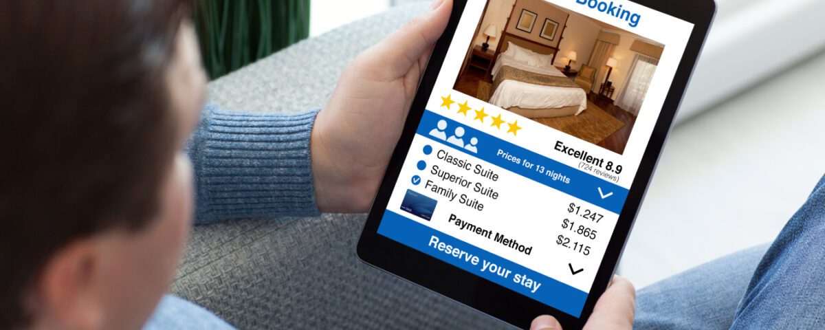 Over the shoulder view of a man holding an iPad tablet looking at hotel reviews and star ratings