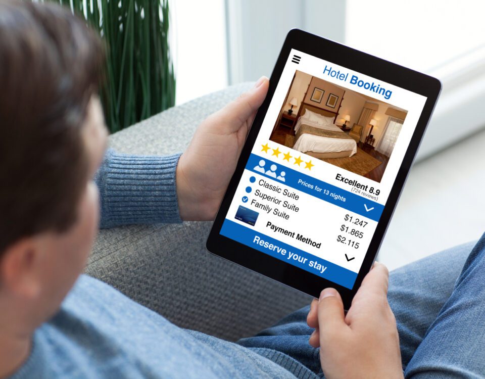Over the shoulder view of a man holding an iPad tablet looking at hotel reviews and star ratings