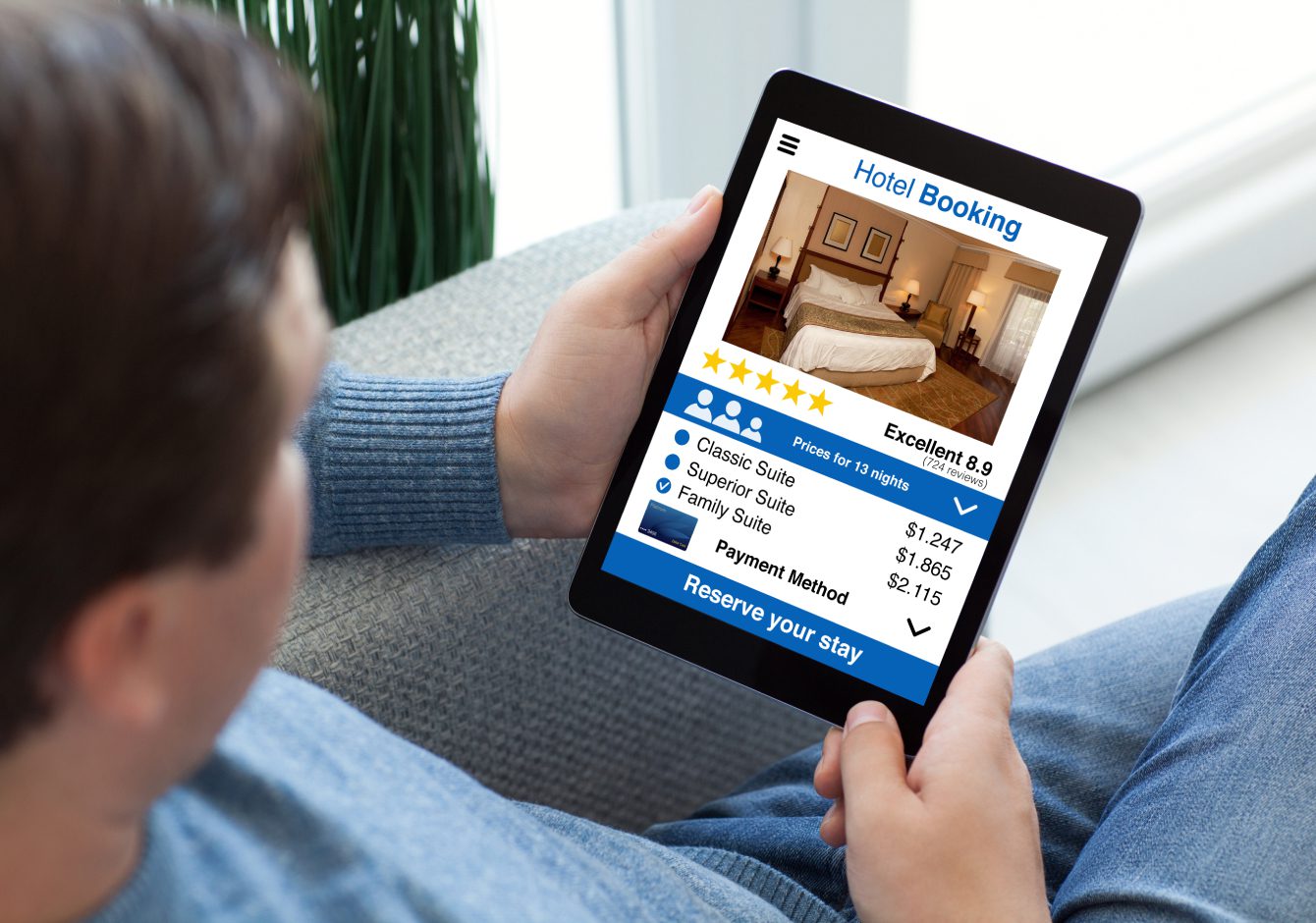 Over the shoulder view of a man holding an iPad tablet looking at hotel reviews and star ratings