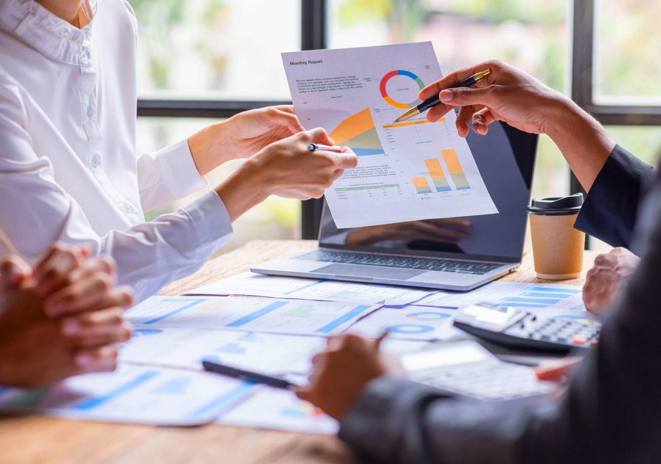 Office team members sitting at desk pointing to data graphs on a sheet of paper