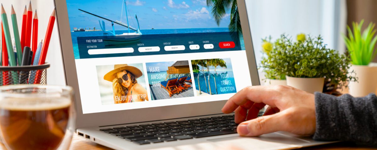 Person sitting at desk using laptop with travel agency holiday booking on screen