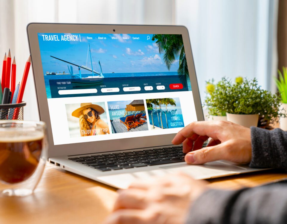 Person sitting at desk using laptop with travel agency holiday booking on screen