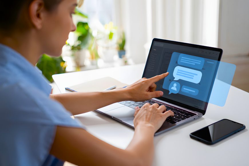 Woman sitting at desk using touchscreen laptop with live chat conversation bubbles on screen